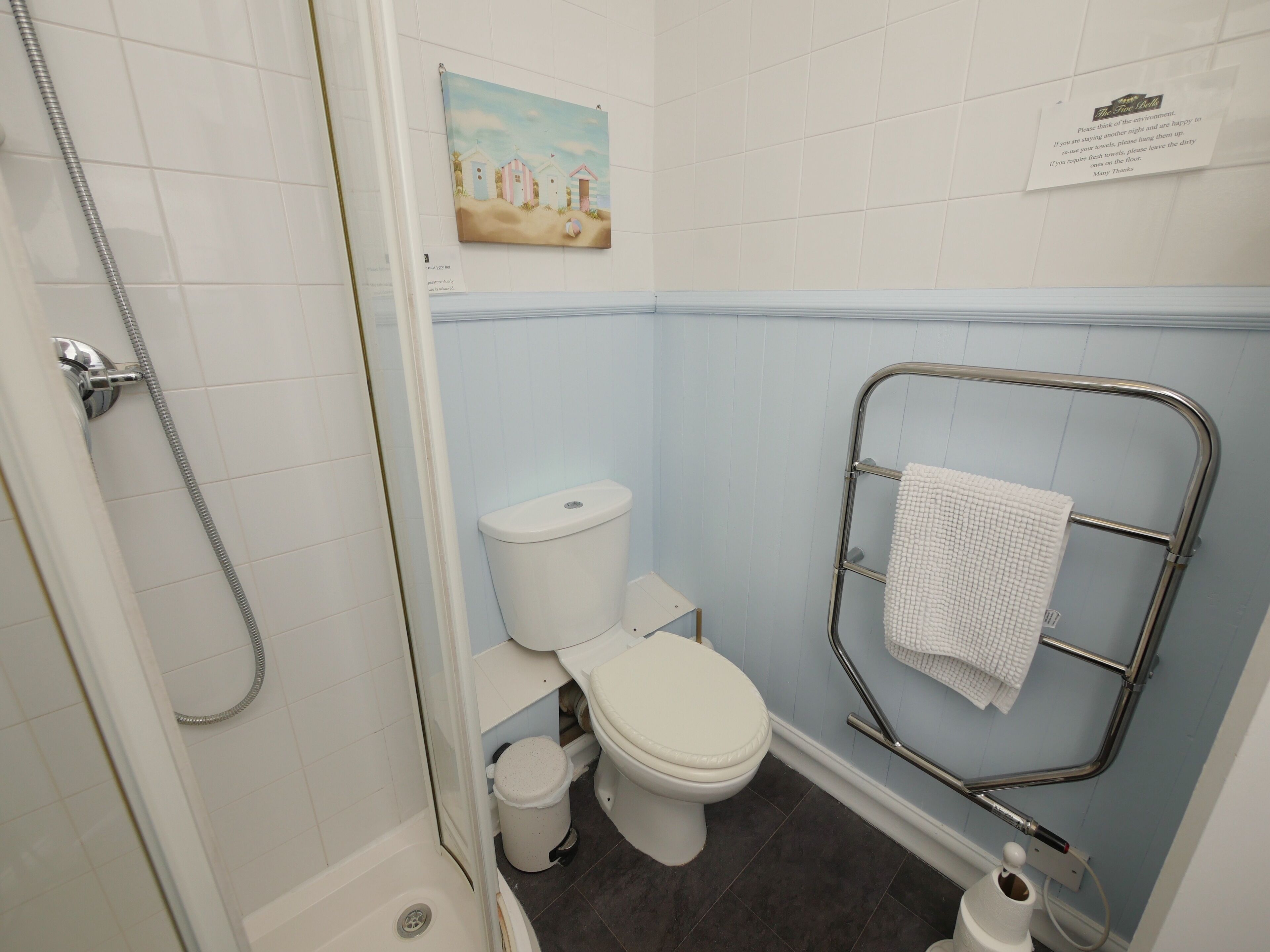 A bathroom with a toilet, a shower, and a towel rack.