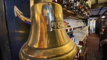 Una campana de bronce con el número 182 en una barra de bar.