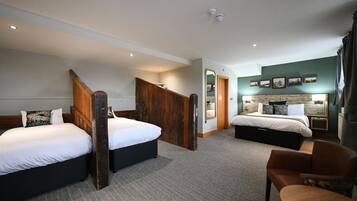 A hotel room with two beds, a wooden staircase, a mirror, a nightstand, and a chair.