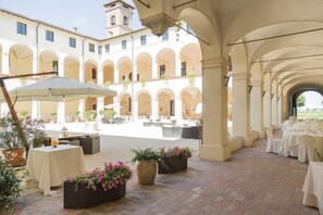 An outdoor patio with tables and chairs, surrounded by arches and potted plants. - Relais Fontevivo (Fontevivo)