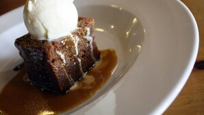 Un dessert surmonté d’une boule de glace, servi dans une assiette blanche.