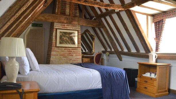 Une chambre à coucher comprenant un lit, une table de chevet, une lampe, une commode et un miroir.