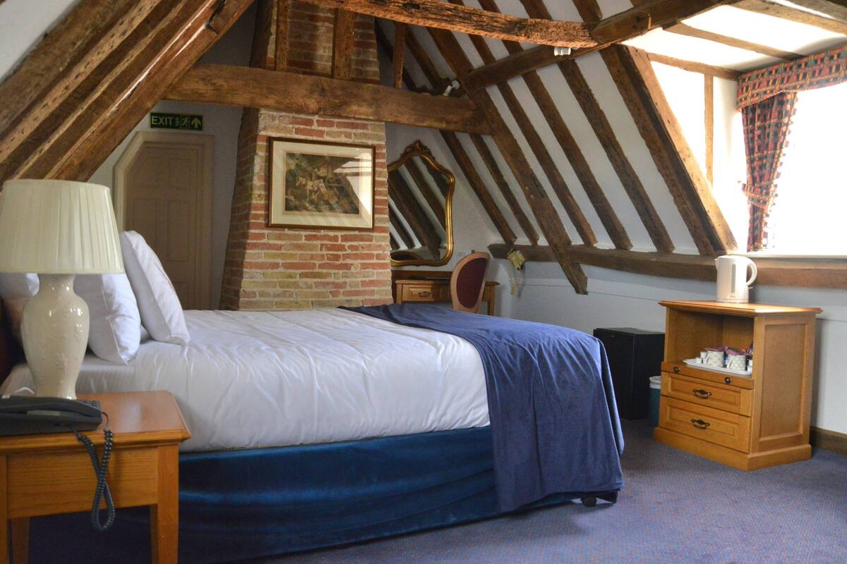 Une chambre à coucher comprenant un lit, une table de chevet, une lampe, une commode et un miroir.