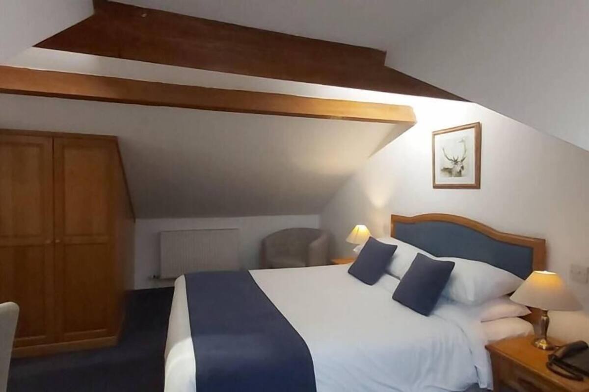 Une chambre à coucher avec un lit, des lampes de chevet, une armoire en bois et un tableau encadré au mur.