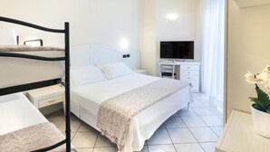 A hotel room with a bed, a desk, a chair, a TV, and an air conditioning unit. - Hotel Fenice (Cervia)