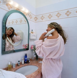 Un baño con lavamanos de mármol, espejo con marco verde y artículos de aseo sobre la encimera.