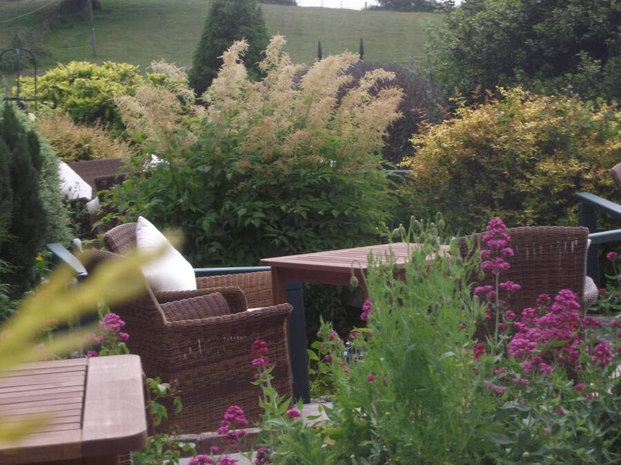 Un patio giardino con mobili in vimini, un tavolo di legno e diverse piante e fiori.
