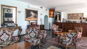 A room with a bar area, antique furniture, and artwork on the walls. - Hotel Negresco (Cervia)