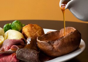 Un plato de pudín de Yorkshire, carne asada, salsa de pudín de Yorkshire y verduras.
