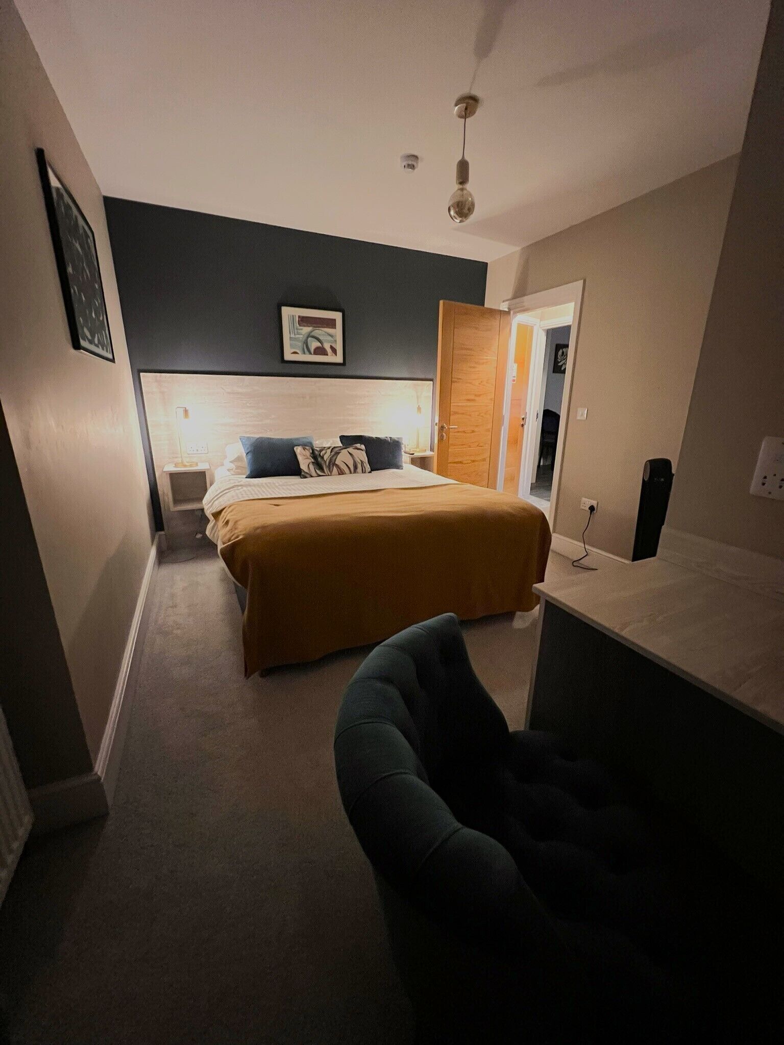 A bedroom with a bed, bedside table, and a chair.