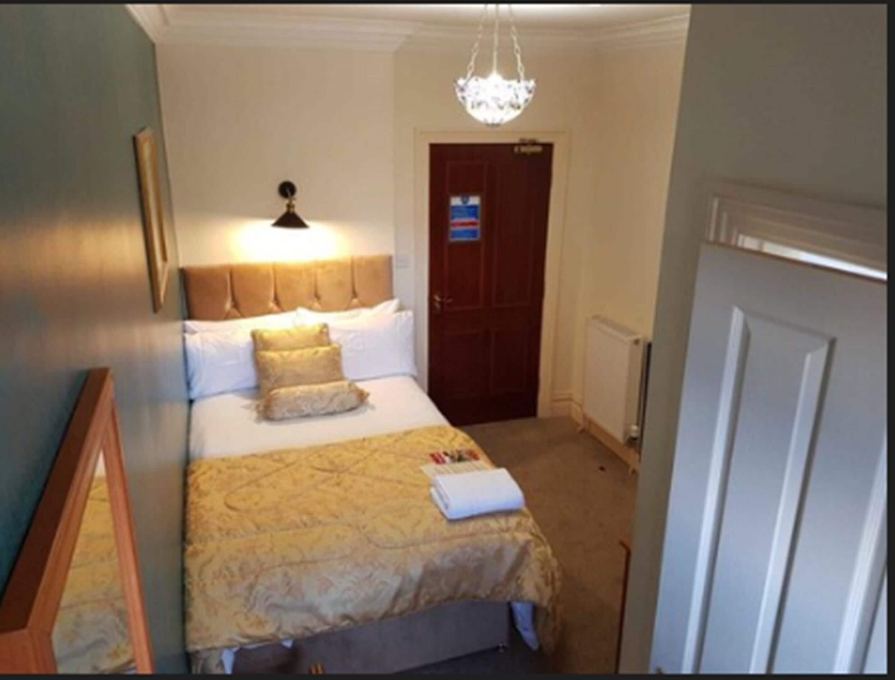 Una habitación de hotel con una cama, una araña y un radiador.