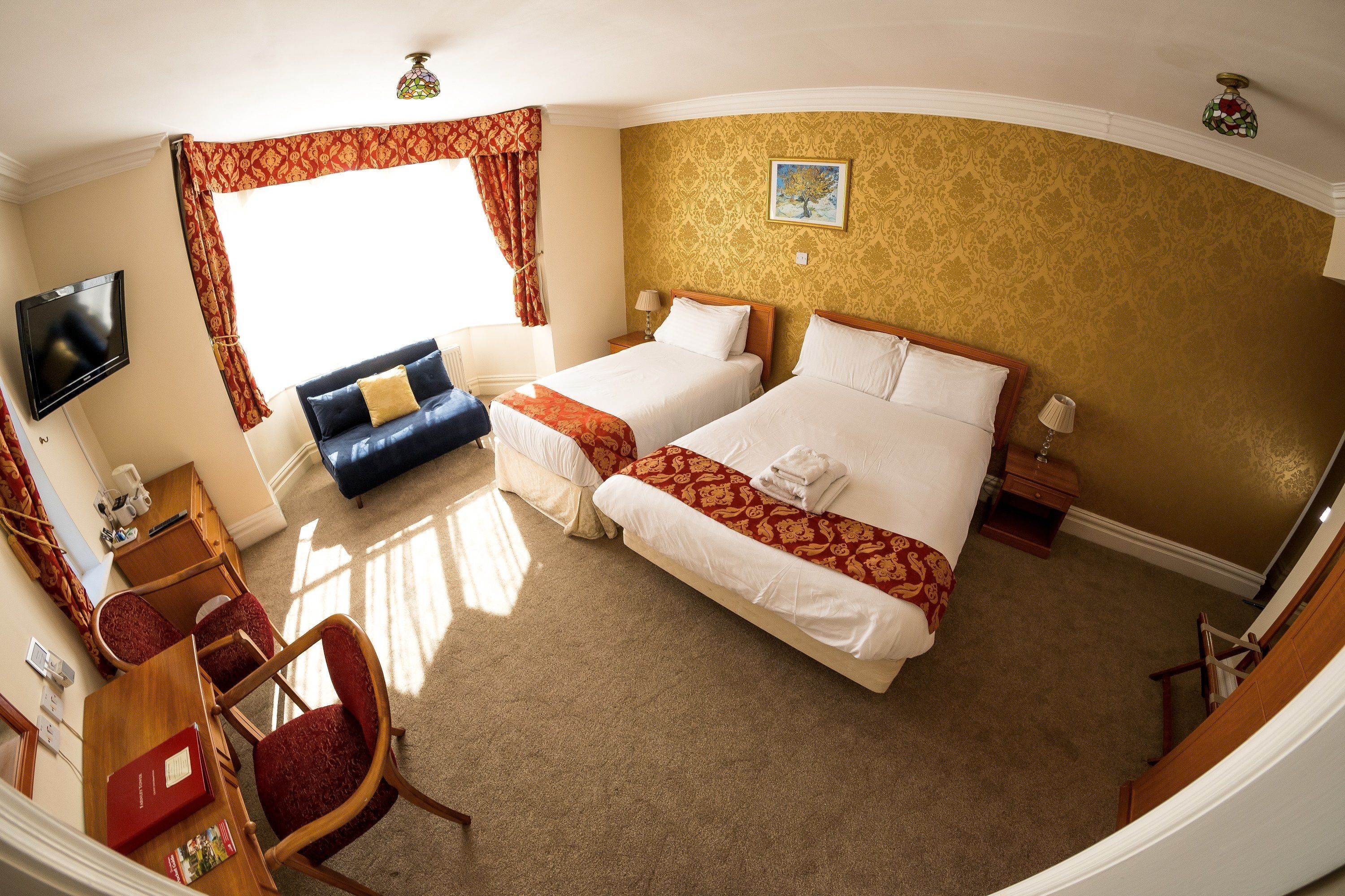 Habitación de hotel con dos camas, televisor, escritorio y una silla.