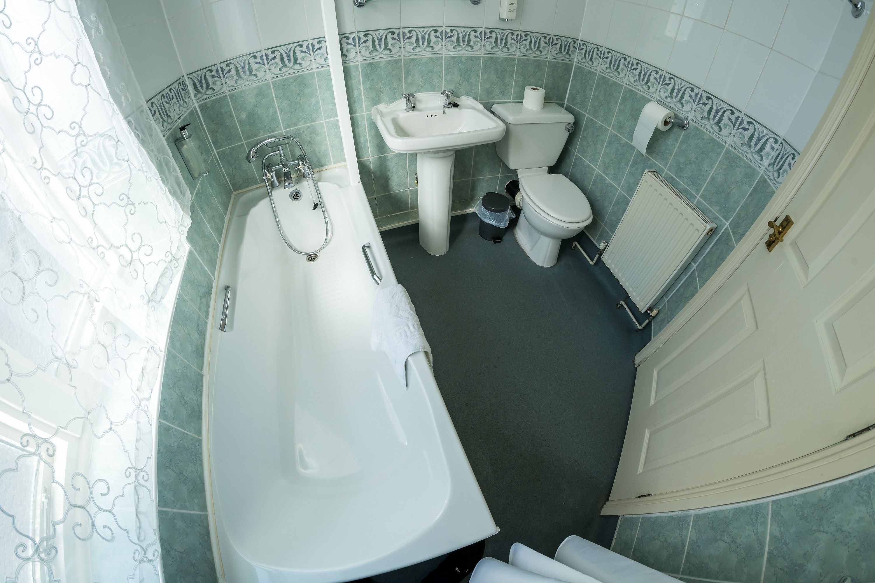 Un baño con bañera, lavabo, inodoro y un radiador.