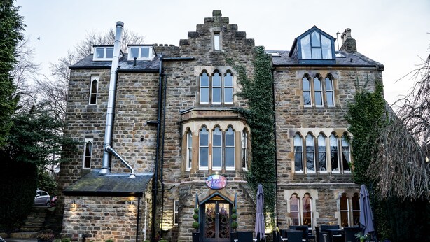 A stone building with a prominent entrance, large windows, and outdoor seating area. - Farnley Tower Guesthouse (Durham)
