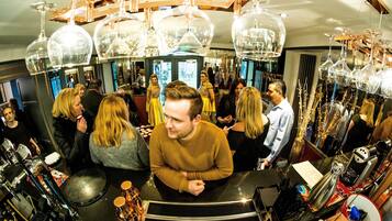A bar area with round tables, hanging glass chandeliers, and a variety of bar equipment.