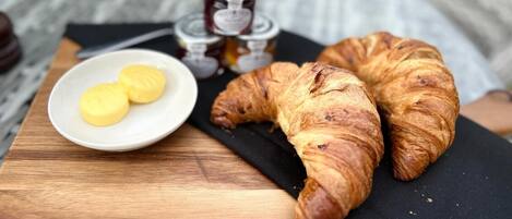 A wooden table with two croissants and a small plate of butter.