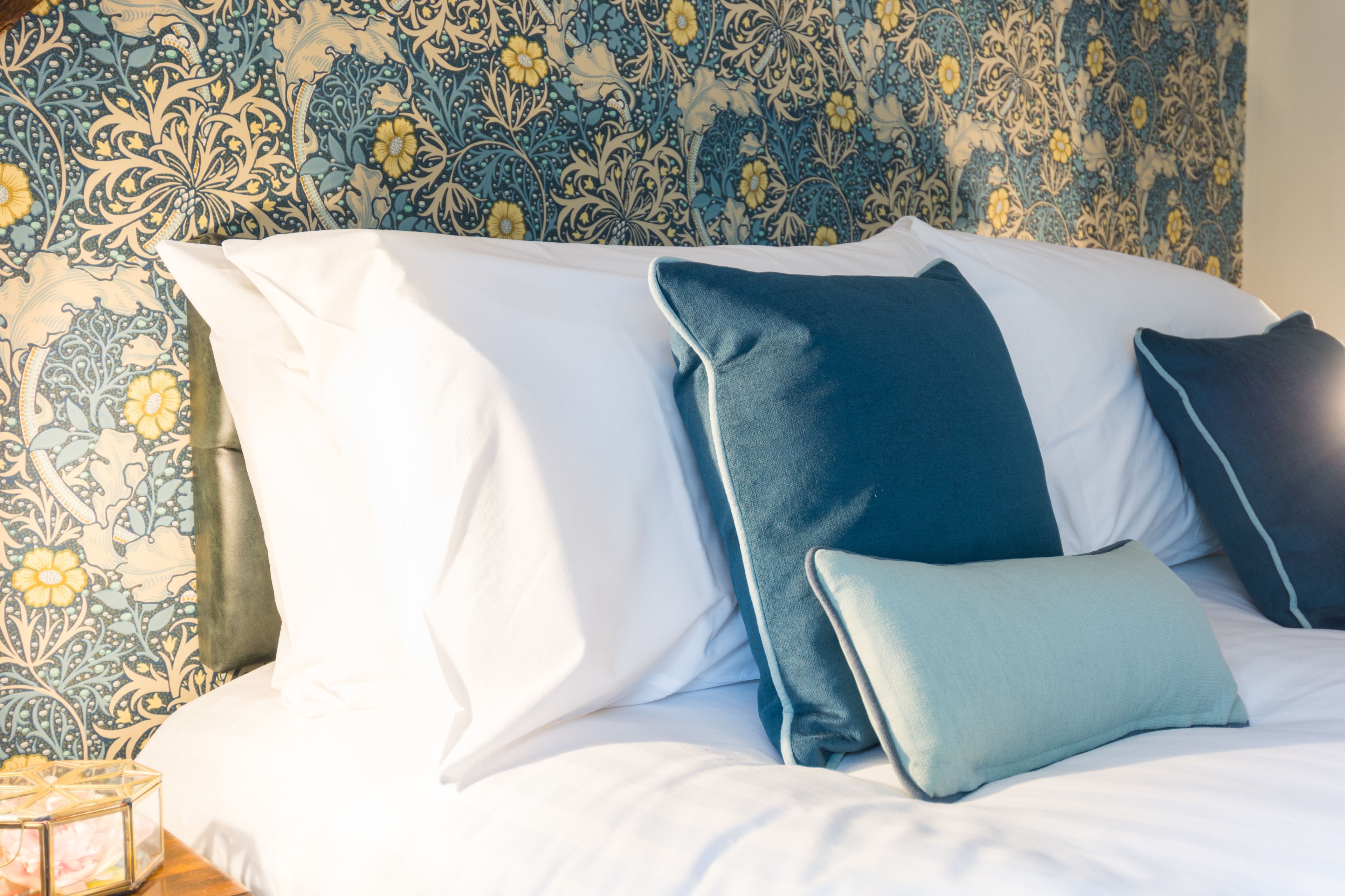 Una cama bien hecha con múltiples almohadas y un cabecero decorativo.