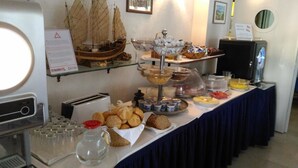 Buffet com diversos alimentos, incluindo pão, doces e uma réplica de navio.