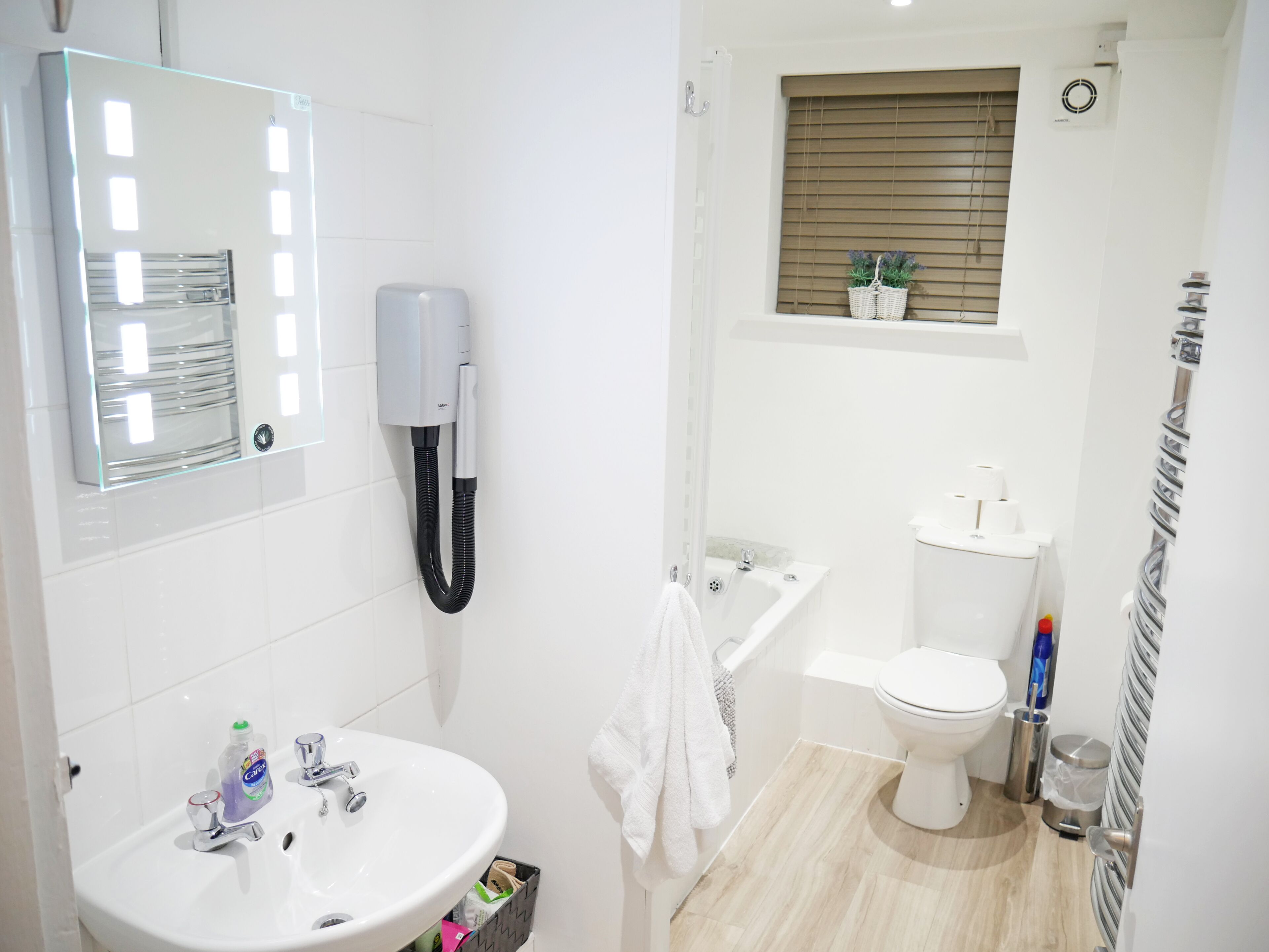 Un baño moderno con lavamanos, espejo y retrete blancos.