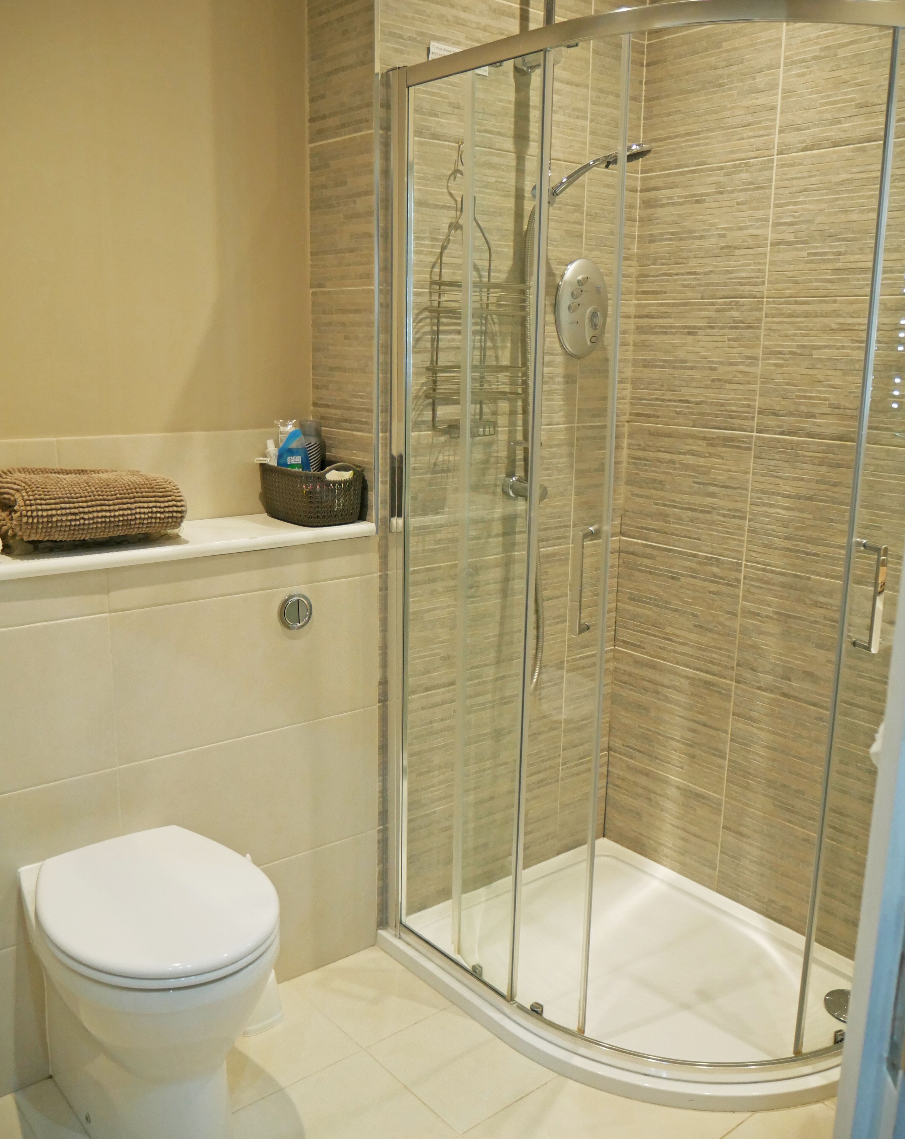 Un bagno con doccia vetro-murata, un water e un lavabo con articoli da toilette.