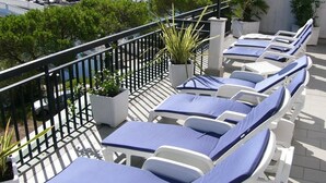 A rooftop terrace with sun loungers and potted plants. - Hotel Serena (Grado)