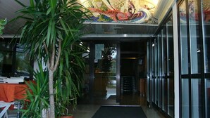 A hotel lobby with a tiled floor, a reception desk, and a large mural on the ceiling. - Hotel Serena (Grado)