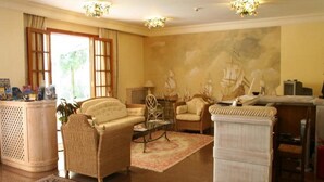Una sala de estar con muebles de mimbre, una mesa de centro y un mural de barcos en la pared.