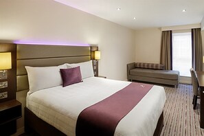 A hotel room with a large bed, a sofa, a desk, and a window with curtains. - Premier Inn St Neots A1 Wyboston (St Neots)