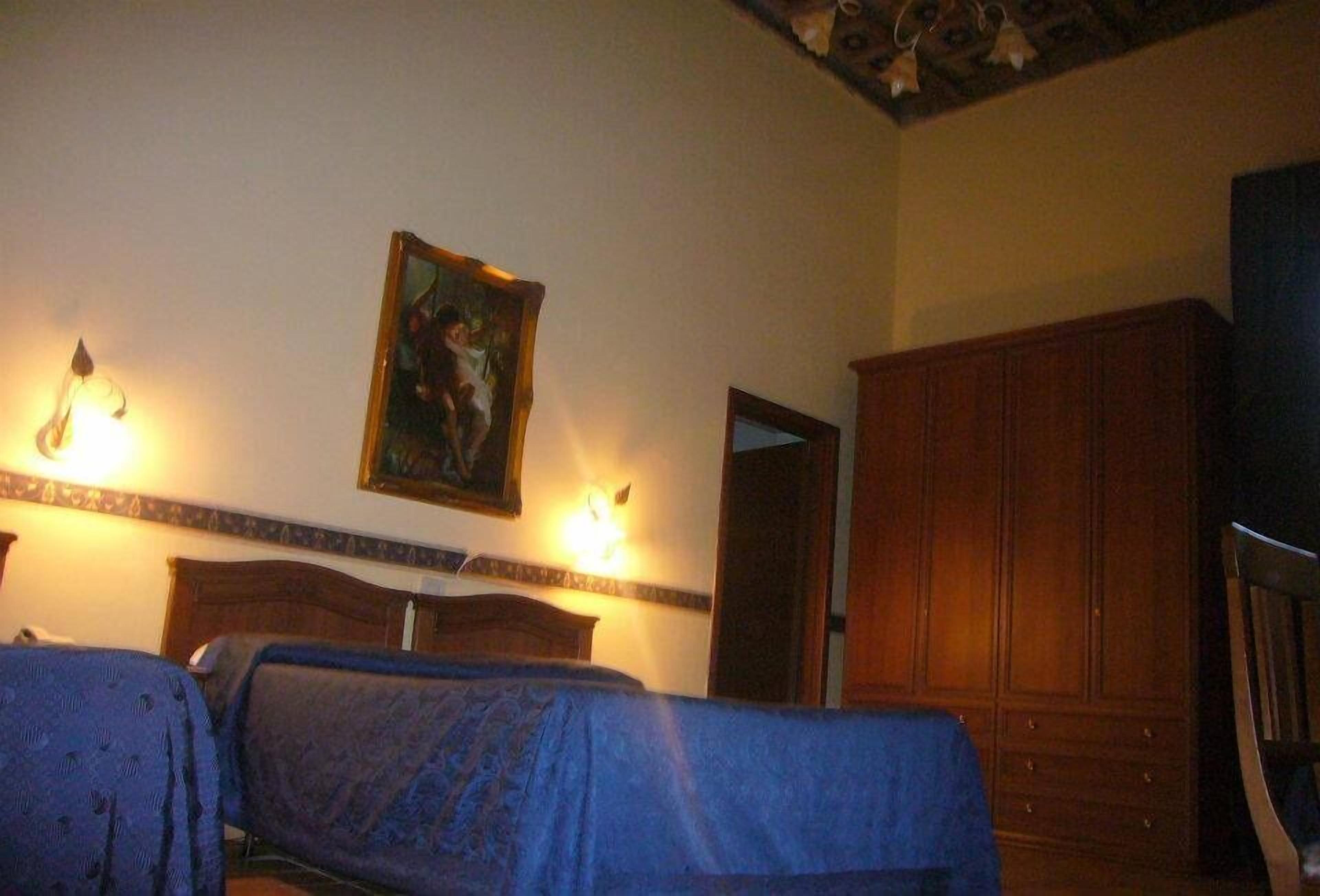 Een hotelkamer met twee bedden, een houten garderobe en een schilderij aan de muur.