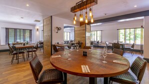 A spacious dining area with a large wooden table surrounded by leather chairs, equipped with wine glasses and cutlery. - Woodcote Hotel (Ellesmere Port)