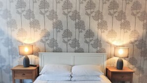 A bedroom with a bed, two bedside tables, and two lamps. - Woodcote Hotel (Ellesmere Port)