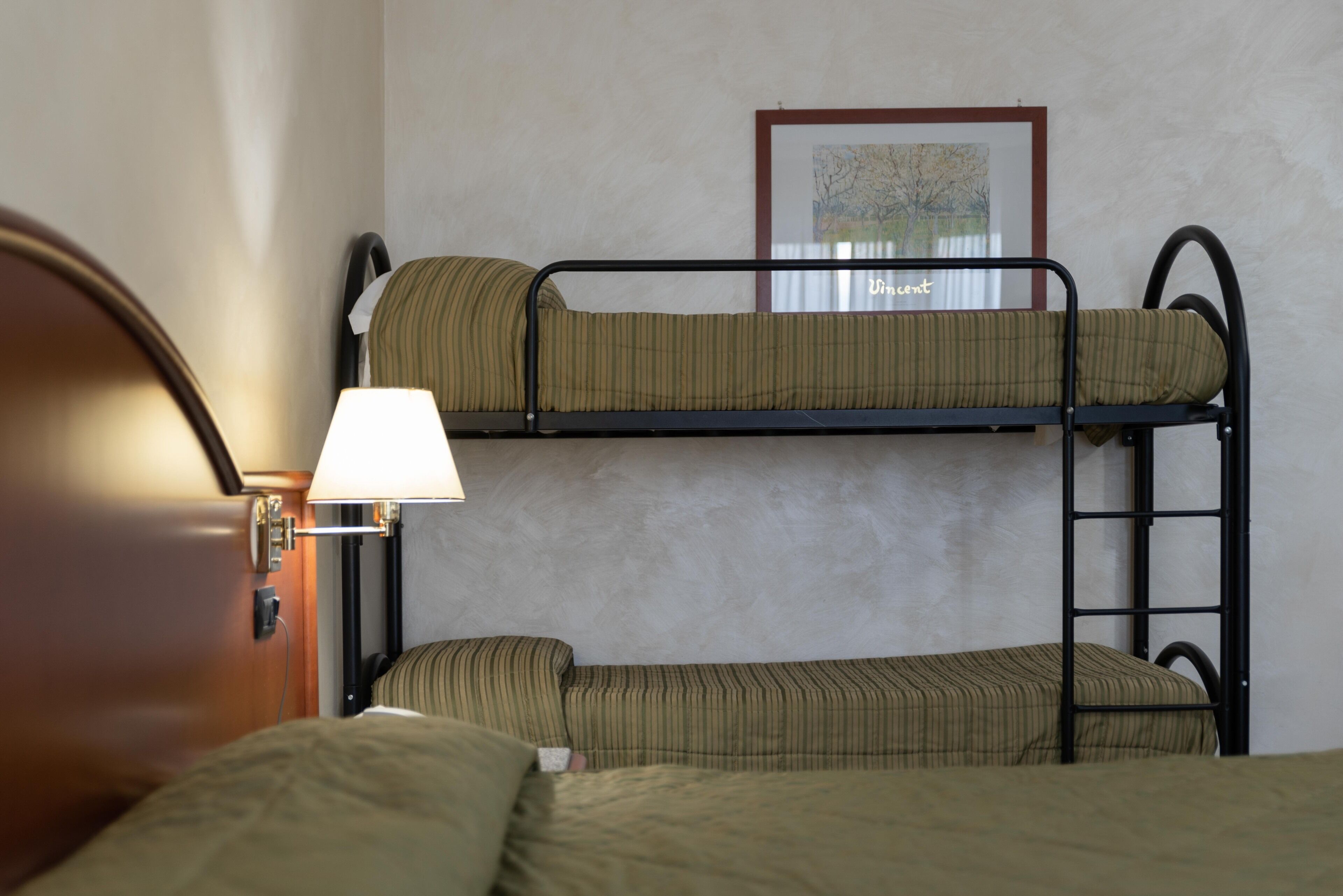 A bunk bed with striped bedding, a lamp, and a framed map on the wall.