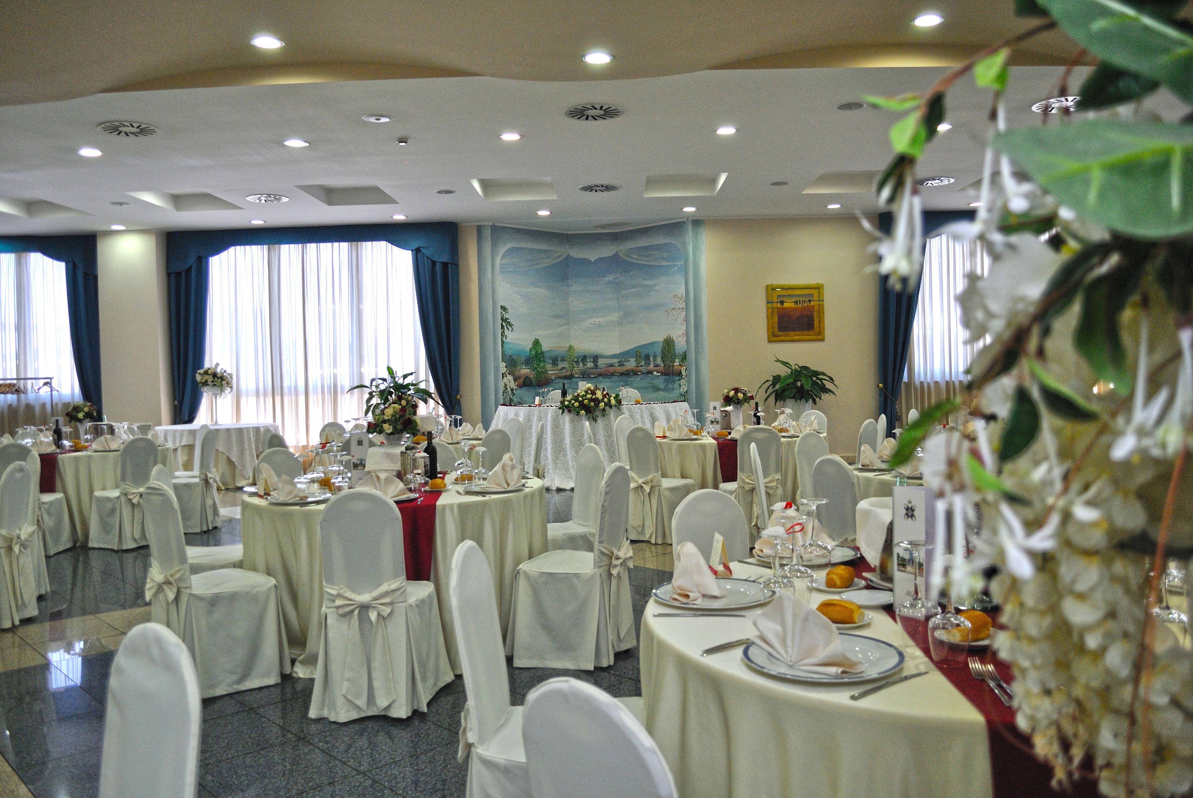A banquet hall with round tables, white tablecloths, and chairs with white sashes.