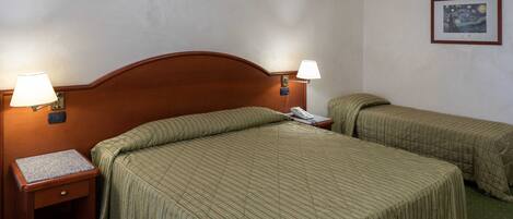 A hotel room with two single beds, each with a wooden headboard, a nightstand with a lamp, and a telephone.
