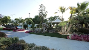 A landscaped garden with a gazebo, palm trees, and a variety of plants. - Edra Palace (Cassino)