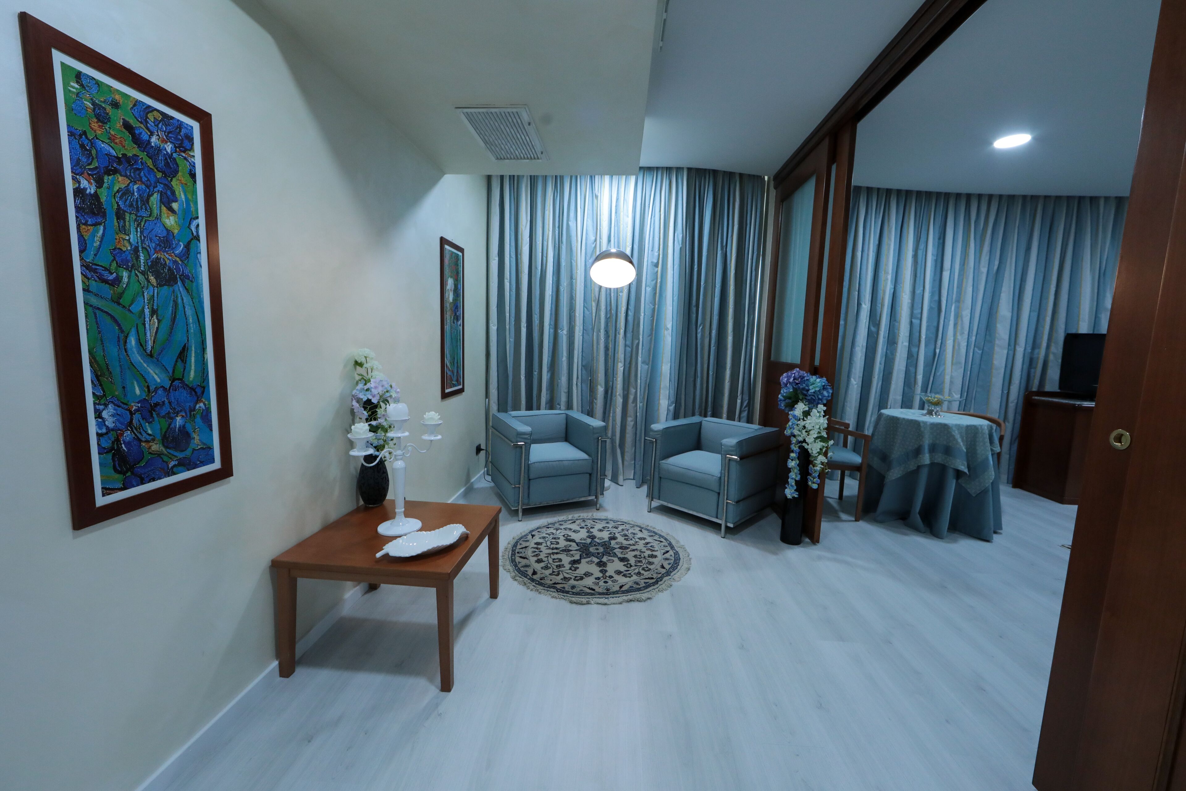 Un salon avec un canapé bleu, une table basse, un tapis et un tableau accroché au mur.