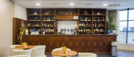 A bar area with multiple seating arrangements and a variety of bottles on shelves.