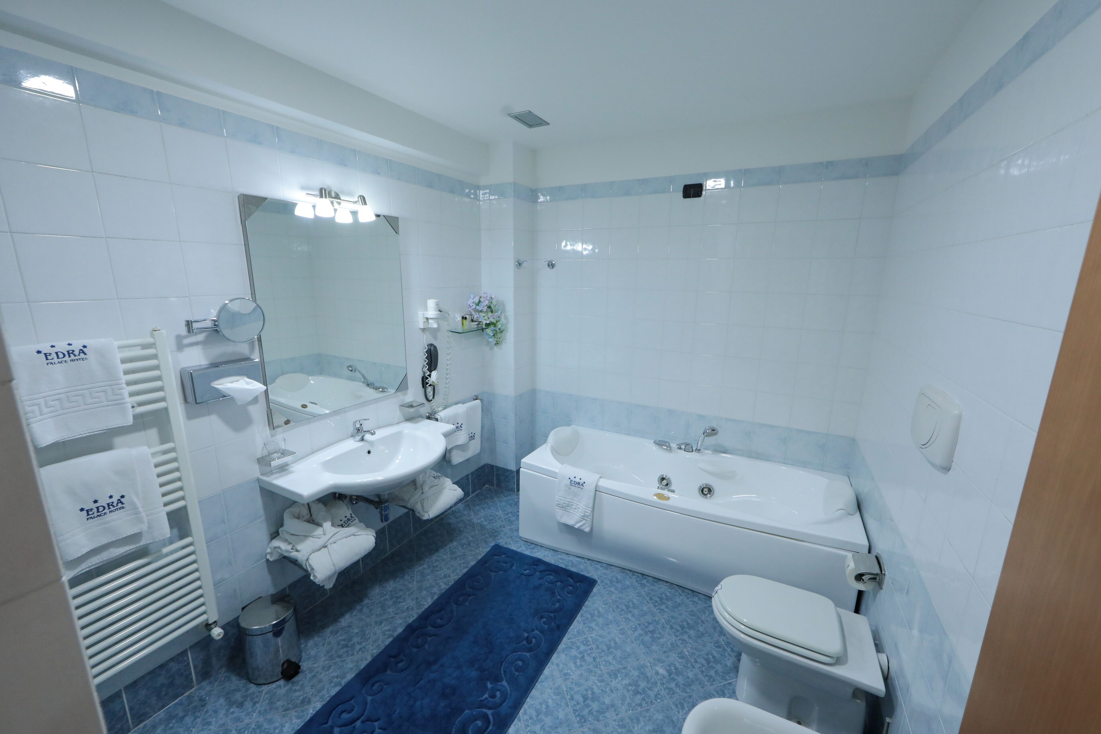 Un baño moderno con una bañera, dos lavamanos, un inodoro y una alfombra azul estampada.