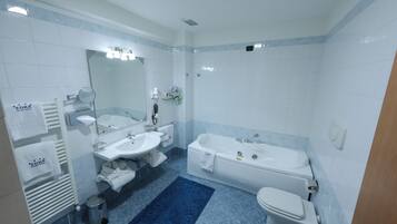 Un baño moderno con una bañera, dos lavamanos, un inodoro y una alfombra azul estampada.