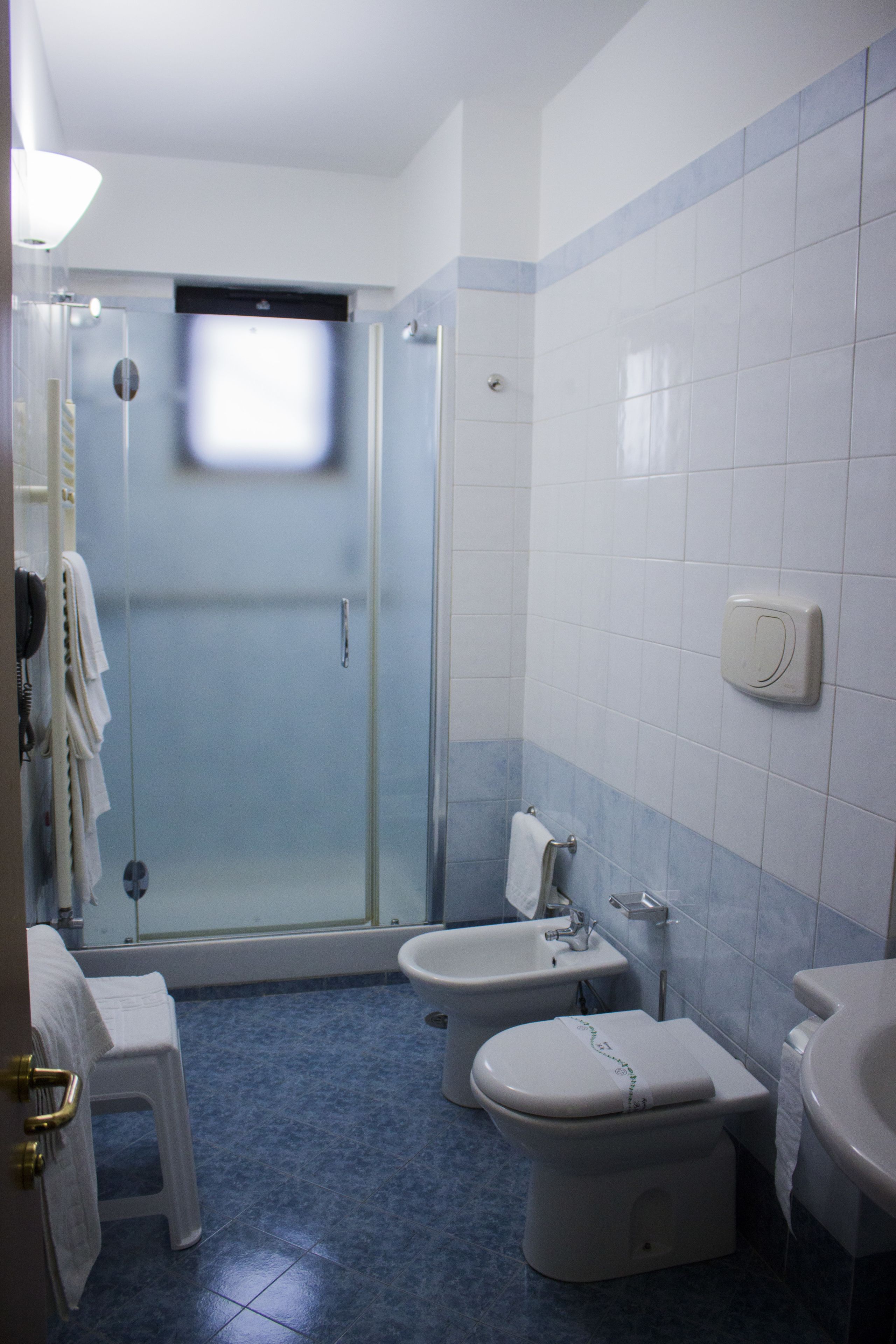 A bathroom with a shower, bidet, toilet, and sink.