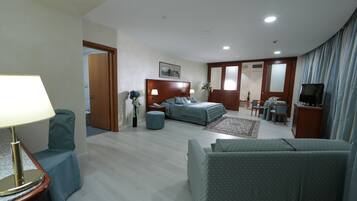 A hotel room with a bed, a sofa, a TV, and a desk.