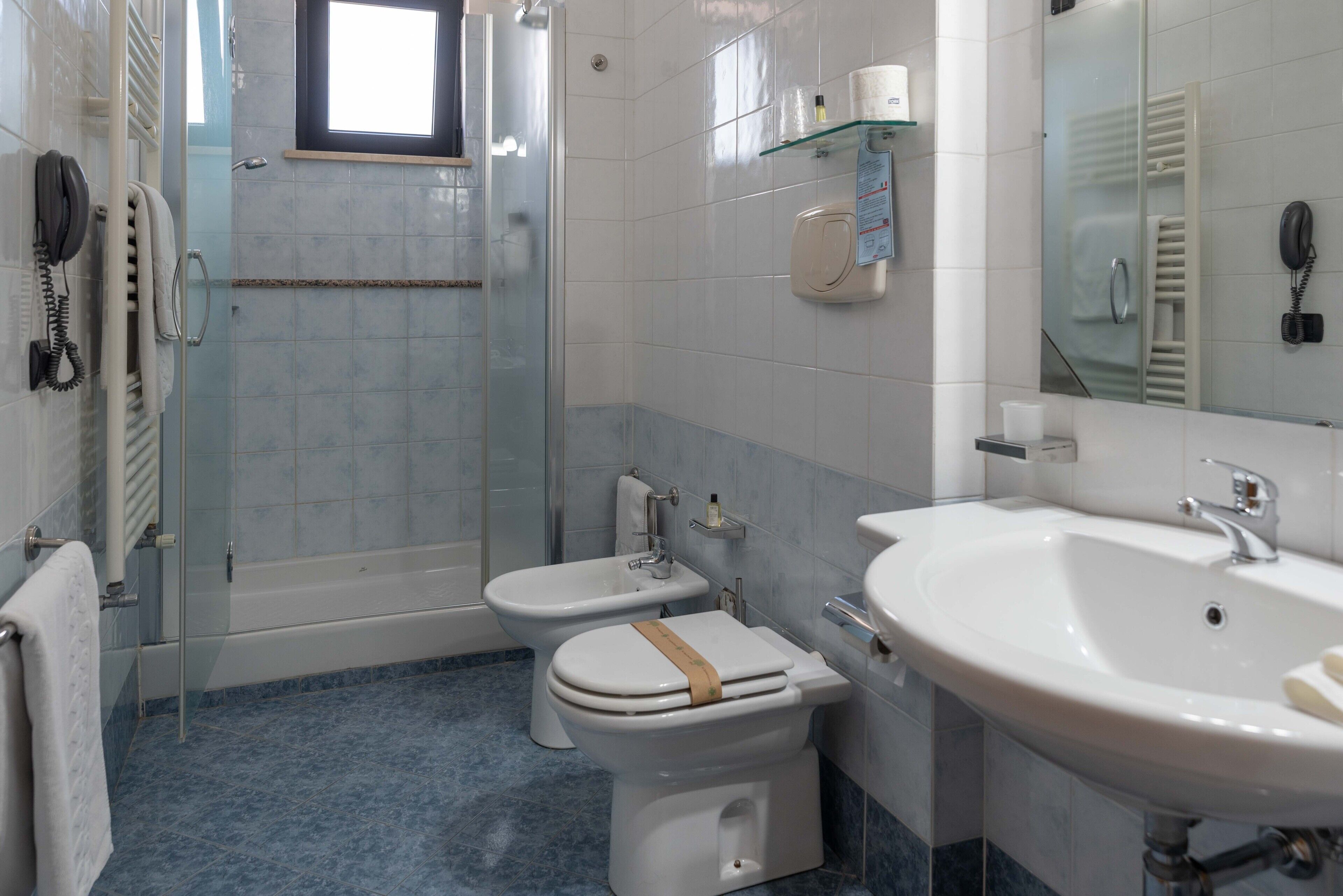 A bathroom with a bathtub, a bidet, a toilet, a sink, and a glass shower enclosure.