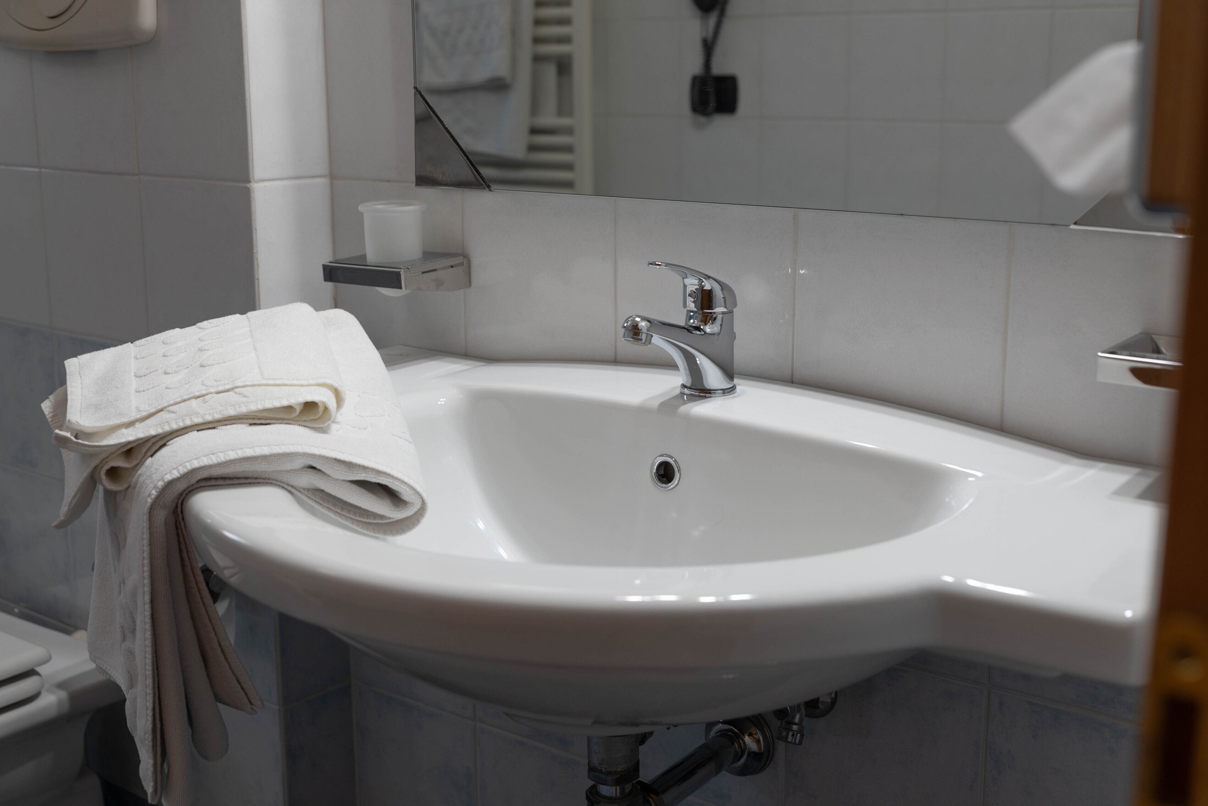 A bathroom with a white sink, a towel rack, and a mirror.