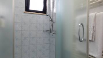 A bathroom with a glass shower enclosure, a window, and a towel rack.