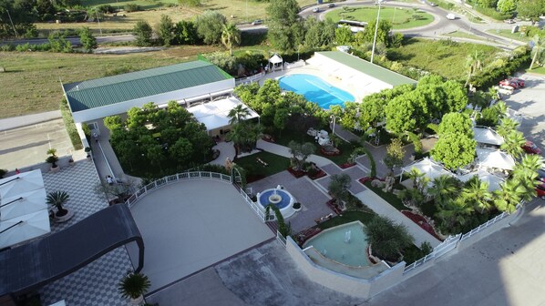 Vue aérienne d’un hôtel doté d’une piscine, d’un patio couvert et d’un jardin aménagé.