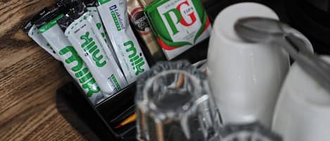 Una bandeja con varios artículos, entre ellos, sobres de leche, una bolsita de té PG Tips, una taza de café y una cuchara.