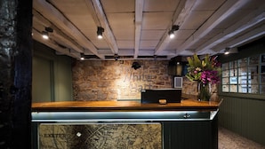 A reception desk with a map of Exeter, a stone wall, and a flower arrangement. - White Hart, Exeter by Marston's Inns (Exeter)