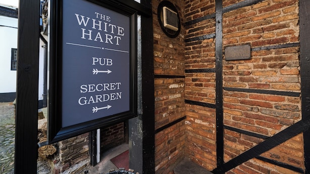 A sign for The White Hart Pub with a brick wall and black beams. - White Hart, Exeter by Marston's Inns (Exeter)