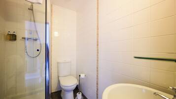Une salle de bain avec une douche à parois de verre, des toilettes et un lavabo.