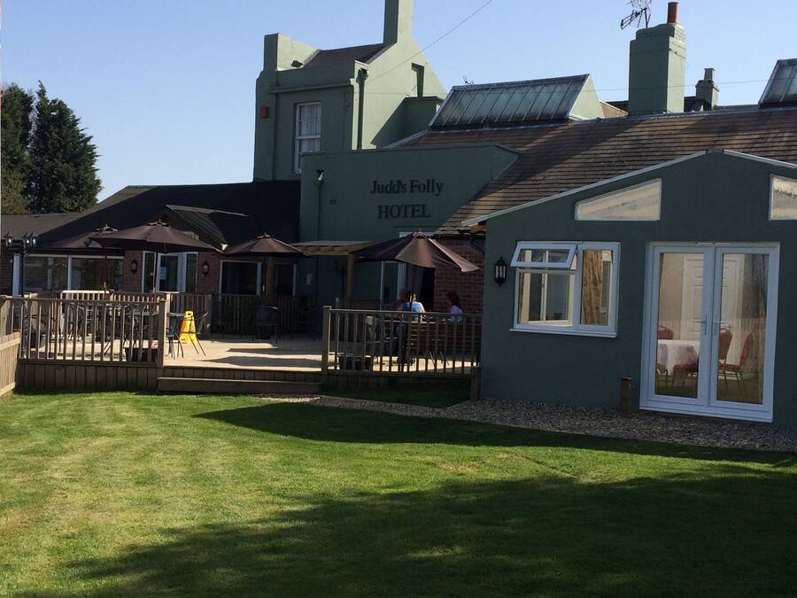 Een hotel met terras en een bord waarop staat 'Judd's Folly Hotel'.